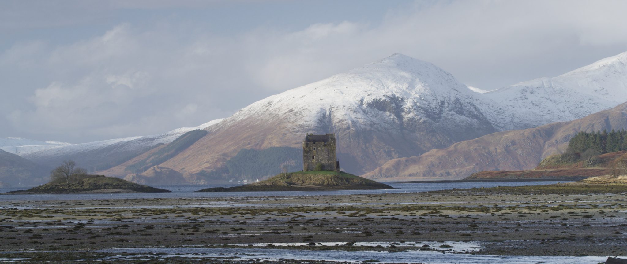 Castle Stalker and the snow clad hills of Mull, Scotland.